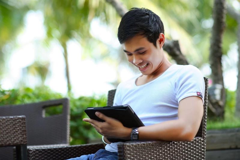 Smiling man with a tablet looking at how SEO and your social media footprint work together