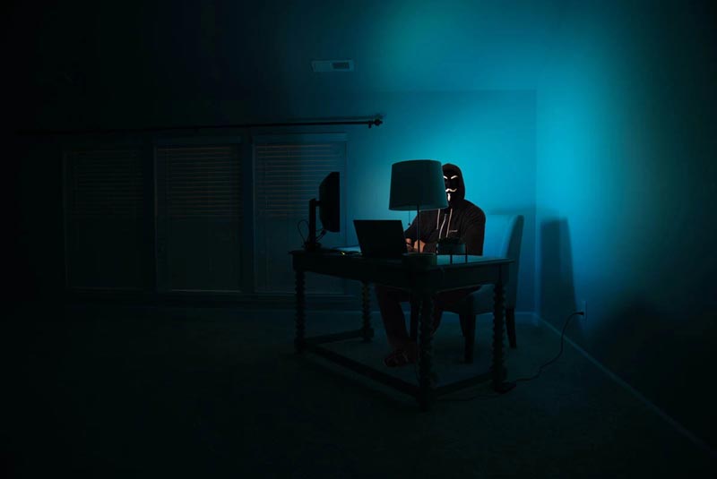 hacker sitting at a computer looking at social media accounts