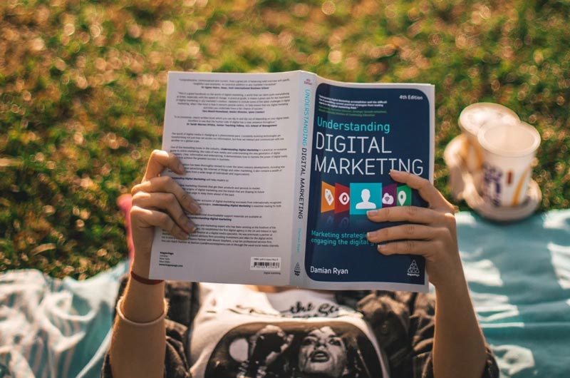 Someone reading a digital marketing book titled filled with terms in the digital world you should know in 2021