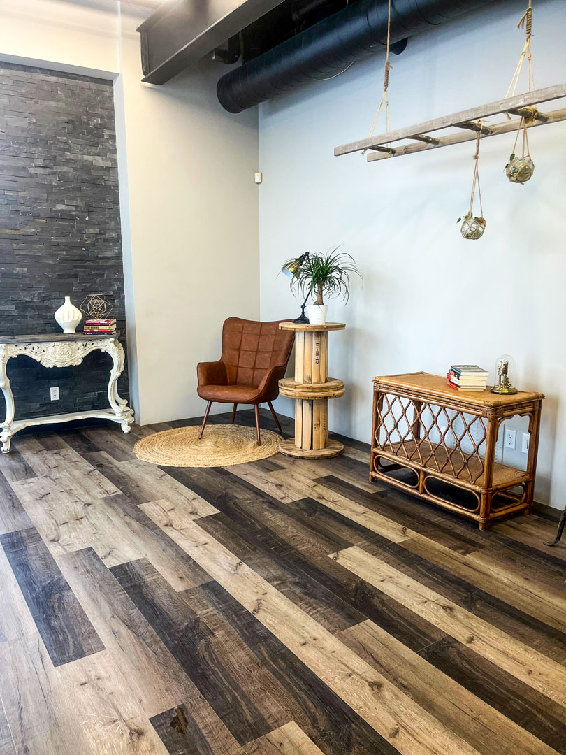 The Lounge provides natural light with a touch of masculine sophistication with white walls, wooden floor, and small rock accent wall.